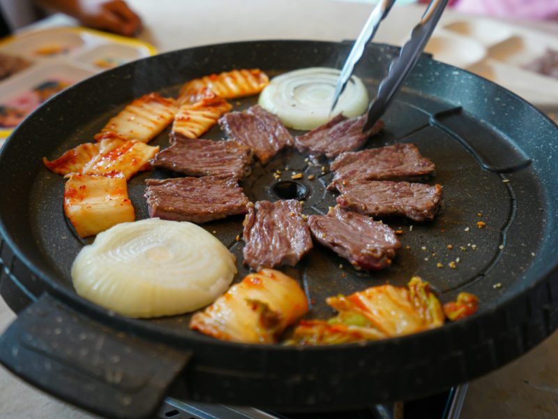 Delicious Korean barbecue featuring beef, onions, and kimchi. Perfect for food lovers.